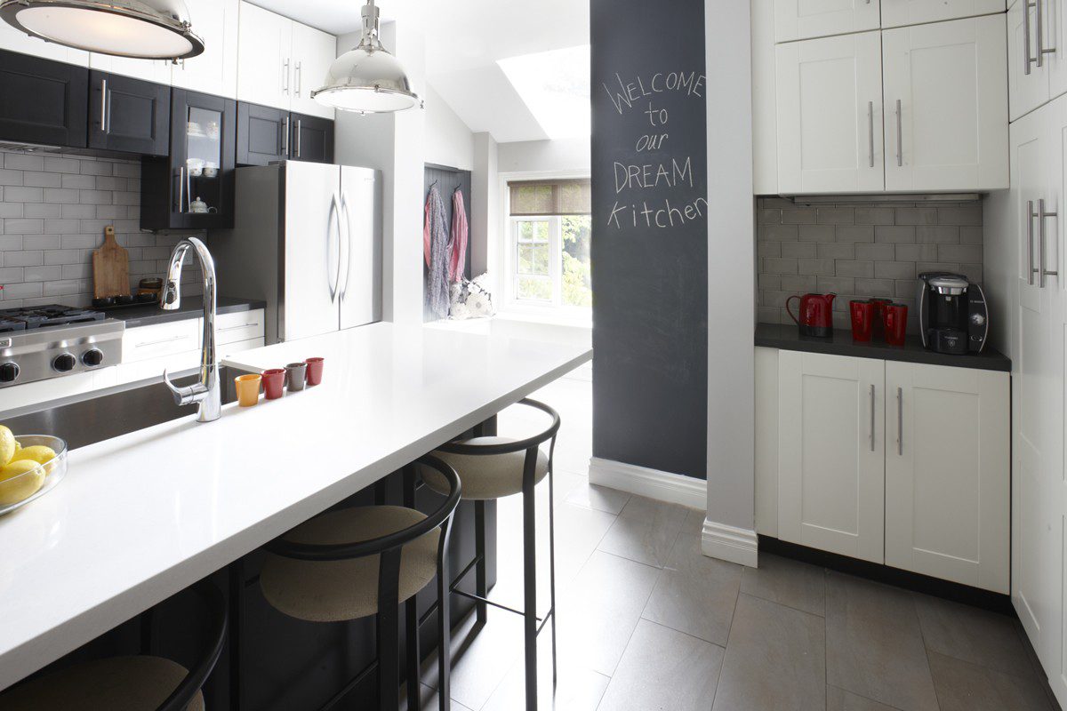 A black and white kitchen with a chalkboard wall.
