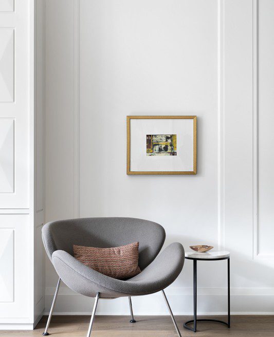 A grey chair sits in front of a white wall.