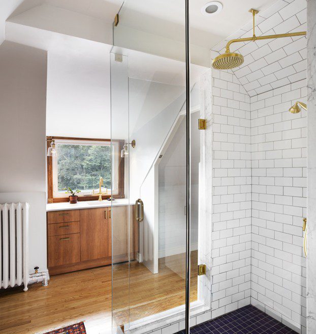 A bathroom with a glass shower stall and blue rug.