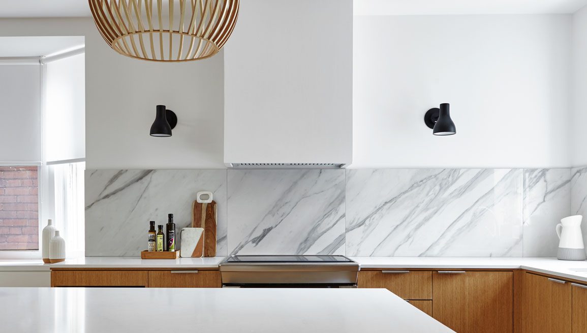 A modern kitchen with marble counter tops and wooden cabinetry.
