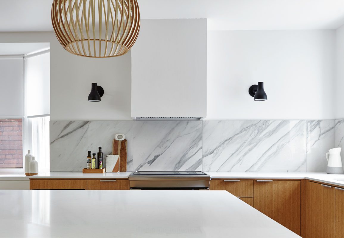 A modern kitchen with marble counter tops and wooden cabinetry.