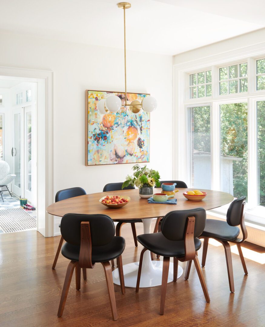 A dining room table with six chairs and a painting on the wall.